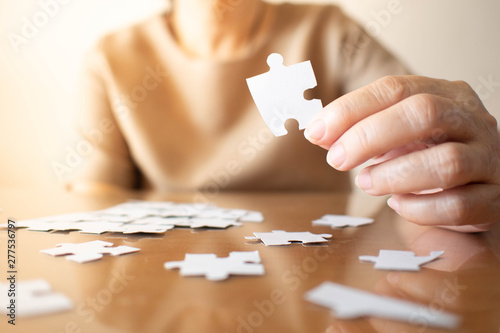 Elderly Female Hands Trying To Connect Pieces Of White Jigsaw Puzzle On Wooden Table Creative Idea For Alzheimer S Disease Dementia Memory Loss And Mental Health Concept Close Up Copy Space Stock Photo