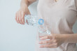 © chatchawan - Woman's hand holding a bottle of water Pouring water into a glass