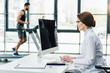 doctor using computer while sportsman running on treadmill during endurance test in gym