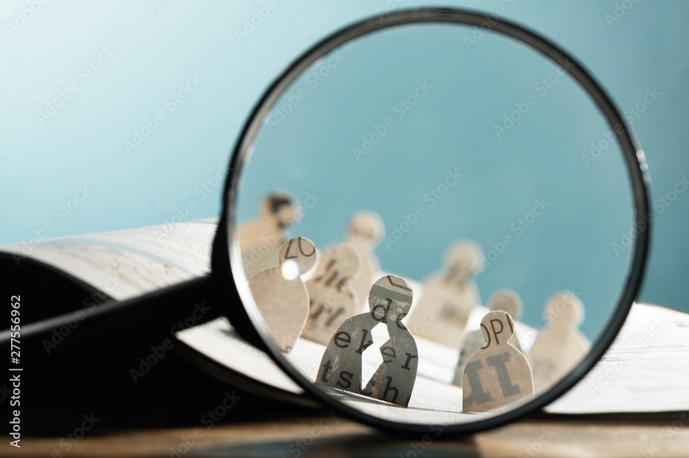 Business recruitment or hiring photo concept. Looking for talent. Icons of candidates are standing on open newspaper under magnifier. - obrazy, fototapety, plakaty 