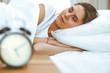 © rogerphoto - Beautiful young and happy woman sleeping while lying in bed comfortably and blissfully smiling