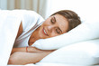 © rogerphoto - Beautiful young and happy woman sleeping while lying in bed comfortably and blissfully smiling