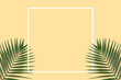 Summer minimal banner with white frame. Green palm leaves on the yellow pastel background with copyspace