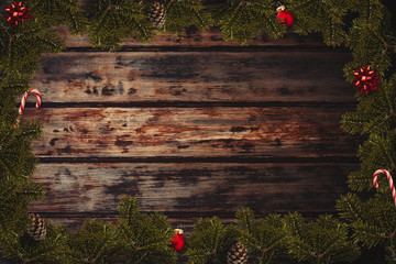 Wall Mural - Christmas flatlay border with wrapped gifts, red balls, canes, bows, cone and green pine branches on the wooden background