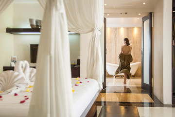 Young woman in the bathroom wearing a robe getting ready to take a bath in the tub, wellbeing body care and beauty concept, spa weekend