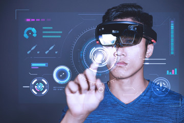 The Asian young man with glasses of virtual reality. Experience VR hololens headset in studio with advanced technology.