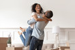 © fizkes - African husband lifting happy wife celebrating moving day with boxes