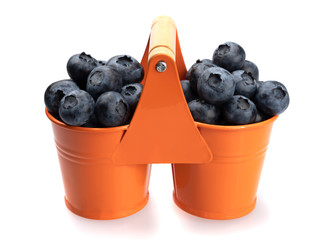 Ripe blueberries (blueberries) in two orange buckets, on a white background. Close-up. Still life.