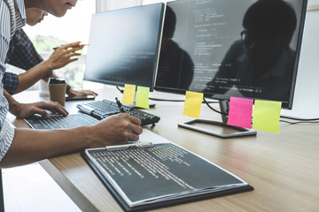 Two professional programmers cooperating at Developing programming and website working in a software develop company office, writing codes and typing data code