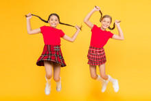 Join Celebration. Cheerful Friends Schoolgirls Jumping Yellow Background. Celebrate Holiday. Scottish Holiday. Kids Girl Wear Checkered Dresses. National Holiday. School Uniform. Scottish Style