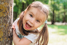 Close-up Portrait Of An Excited Little Girl Laughing In Park