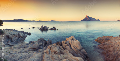 Leinwand Poster  Fantastic azure water with rocks near beach Porto Taverna at sunset
