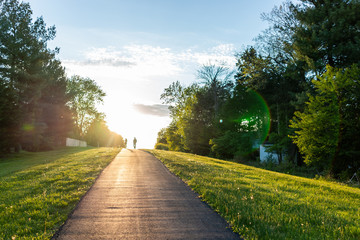 Sugarland Run Stream Valley Trail hike in Herndon, Virginia, Fairfax county in spring with paved path road and silhouette of couple walking