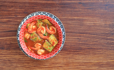 Poster - Delicious Thai yellow curry with shrimp and fried herb vegetable omelet in bowl on wooden table background with copy space.