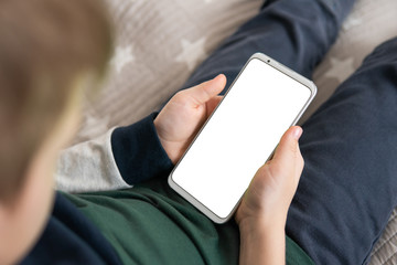 Wall Mural - Smartphone with a white screen in hand child. Phone a for mock up is holding kid. Smartphone with a mock up in the hands of a child. close up top view