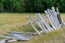Old Wooden Rickety Fence. Abandoned Field With An Old Wooden Fence. Old Broken Wooden Fence. Summer Sunny Day With Blue Sky And White Clouds. The Effects Of The Hurricane. Disaster