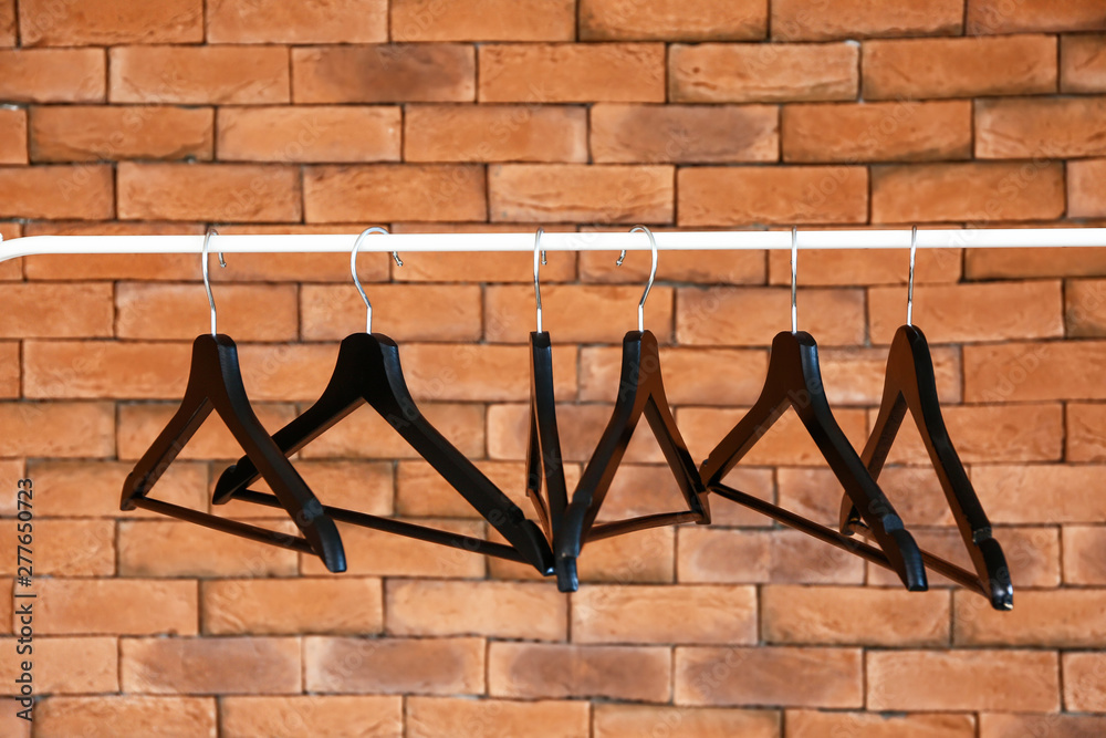 Rack with clothes hangers against brick wall