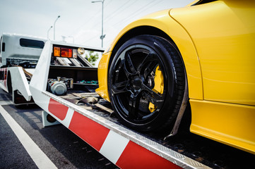 Flat bed tow truck loading a broken vehicle. Roadside service