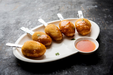 Crispy Veg lollipop recipe made using boiled potato with spices covered with corn flour and bread crumbs coating and then deep fried, served with toothpick or ice cream stock inserted in it with sauce