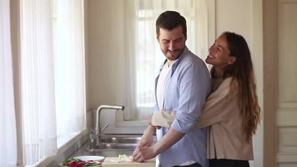 Wall Mural - Husband cooking preparing healthy salad for happy wife at home