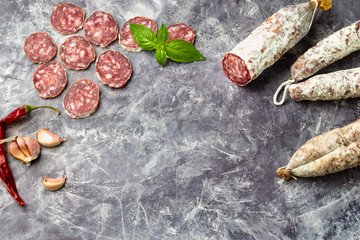 Traditional  thin dried sausage with slices on grey stone background