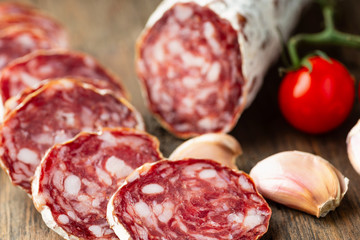 Sliced smoked salami with chilly pepper on wooden background.