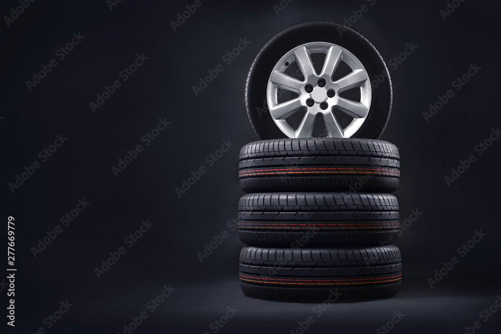 New tires pile on a dark background. Tire fitting background. Copy space. - obrazy, fototapety, plakaty 
