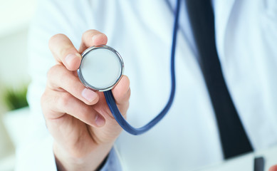 Close up of a doctor's hand, holding a stethoscope outstretched towards the viewer. Medic shop or store, physical and disease prevention, healthy lifestyle concept