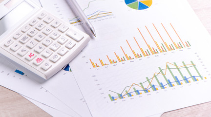 White calculator and report with chart and graph, concept of annual financial profit overview, banking and investment, close up, copy space, macro