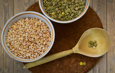 Peas and lentils in white bowls. A wooden spoon. Top view.