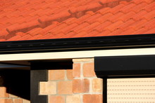 Abstract Terracotta Roof With Sandstone Bricks And Black Trim