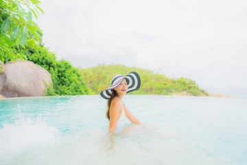 Portrait young asian woman relax smile happy around outdoor swimming pool in hotel resort with sea ocean view