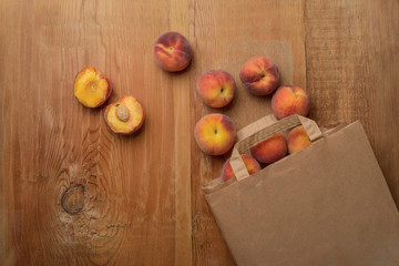 Fresh ripe peaches fruits in paper bag on wooden rustic background. Top view.