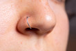 A close up and side view on the nose of a sexy Caucasian girl. Details of a pierced nose with silver hoop. Copy space on the right.