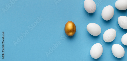 Fotografía One unique golden egg standing opposite of identical ones
