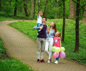 Wall Mural - Happy young family with their two children are walking in summer forest park, parenthood vacations with kids