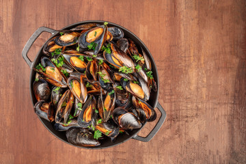 Wall Mural - A full braiser of marinara mussels, shot from the top on a dark rustic background with a place for text