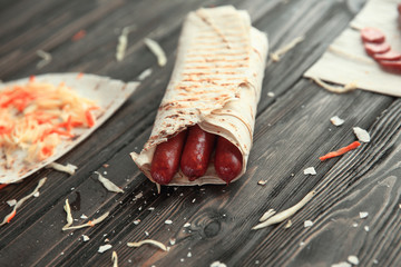 Wall Mural - spicy sausages in pita bread on a wooden table