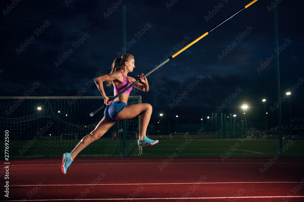 Ready to overcome difficulties. Professional female pole vaulter training at the stadium in the evening. Practicing outdoors. Concept of sport, activity, healthy lifestyle, action, movement, motion. - obrazy, fototapety, plakaty 