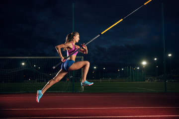 Ready to overcome difficulties. Professional female pole vaulter training at the stadium in the evening. Practicing outdoors. Concept of sport, activity, healthy lifestyle, action, movement, motion.