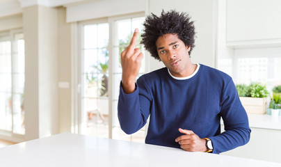 Sticker - Young african american man wearing casual sweater sitting at home Showing middle finger, impolite and rude fuck off expression