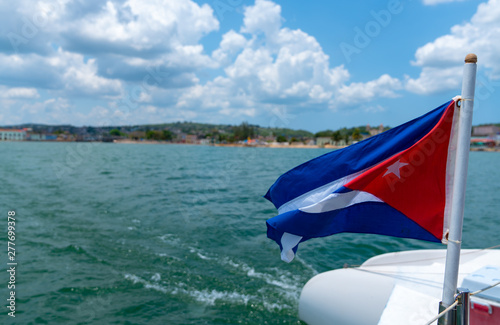 Cuba flag waving on boat at sea near Cuban coastline Canvas Print