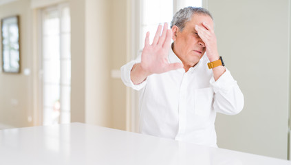 Wall Mural - Handsome senior man at home covering eyes with hands and doing stop gesture with sad and fear expression. Embarrassed and negative concept.