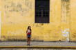 girl standing in front of the yellow street wall in Valladolid, Yucatan, Mexico