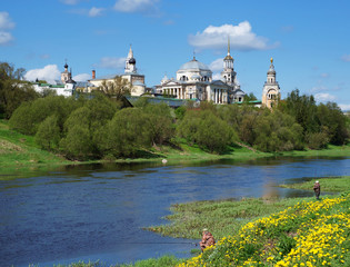 Wall Mural - View of Novotorzhsky Borisoglebsky Monastery and Tvertsa river with fishermen in the foreground. Tver region, Russia. Sunny spring day