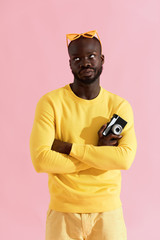 Wall Mural - Black man in yellow fashion clothes with photo camera on pink