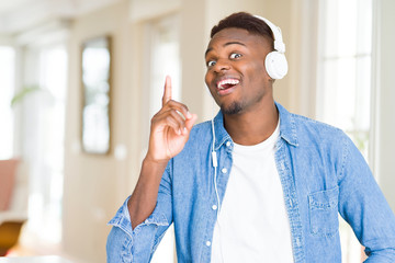 Poster - African american man wearing headphones listening to music pointing finger up with successful idea. Exited and happy. Number one.