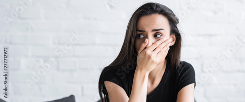 Fotografía scared woman holding hand on face and looking away while suffering from panic at