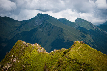 MORZINE, FRANCE. A mountain biker and a hiker sharing a trail high in the French Alps. Dramatic peaks and ominous sky behind.