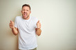 © Krakenimages.com - Young handsome man wearing casual white t-shirt over isolated background excited for success with arms raised and eyes closed celebrating victory smiling. Winner concept.
